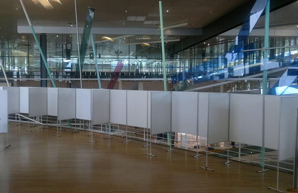 Weiße Combino Messewände stehen aneinander gereiht in einer Ausstellungshalle, sie bilden eine mobile und bespielbare Ausstellungswand.