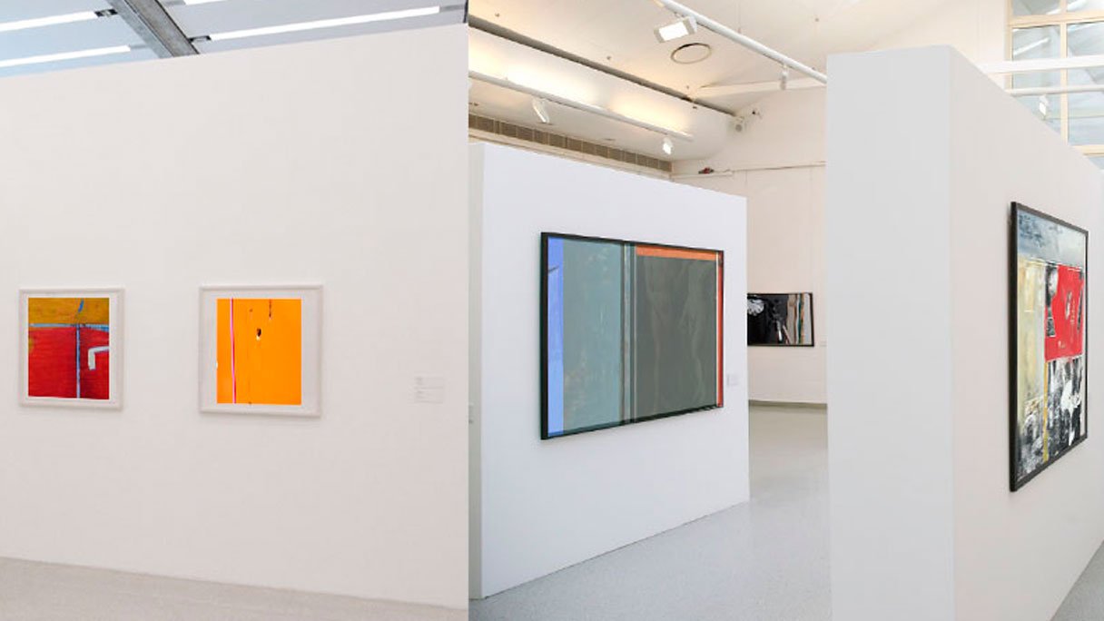 Ausstellungsbau: Ein Ausstellungsraum mit weißen Wänden, an denen Bilder in verschiedenen Größen gehängt sind.